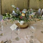 A lovely table setting of flowers in the middle of the tipi for a wedding.